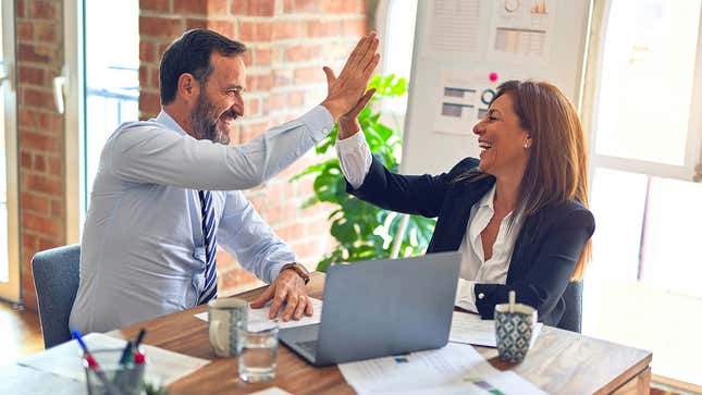 A man and a woman high-fiving in a corporate office