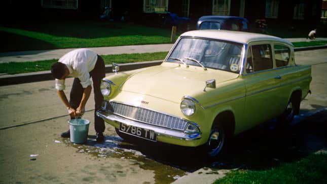 A young man washes the family Ford Anglia car on an Essex estate in the early 1960s