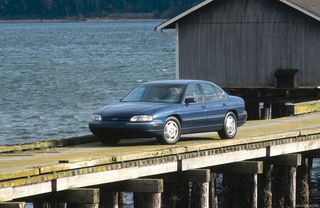 A blue Chevy Lumina parked on what looks like a pier on a lake. 