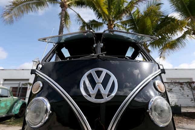 A close-up of a black '55 VW bus with safari windows which hinge up from the top and open completely.