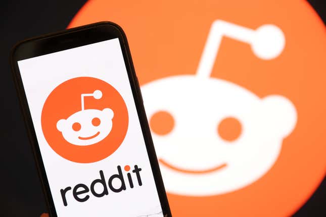 The Reddit logo is displayed on the screen of an iPhone.