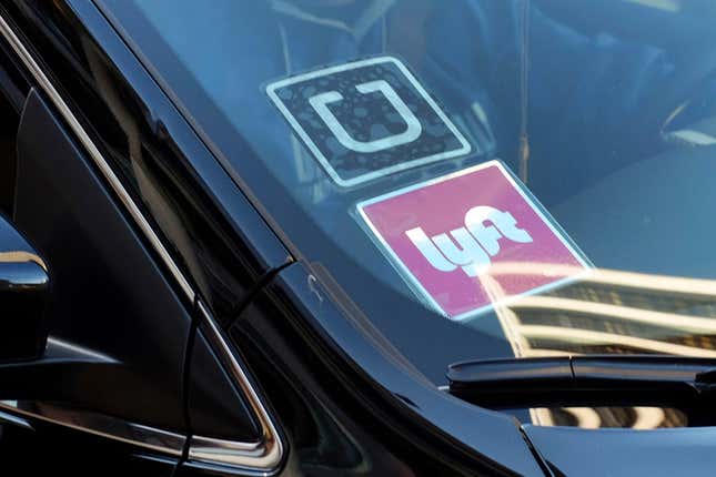 FILE - A ride share car displays Lyft and Uber stickers on its front windshield in downtown Los Angeles, Jan. 12, 2016. The ride-hailing companies Uber and Lyft said they will delay their plans to stop operating in Minneapolis after city officials decided Wednesday, April 11, 2024, to delay an ordinance requiring increased pay rates for drivers. (AP Photo/Richard Vogel, File)