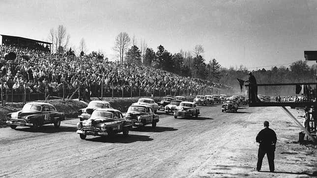 A black and white photo of the start of a NASCAR race. 