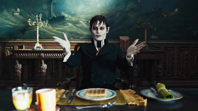 Johnny Depp as a vampire sits at a table. 