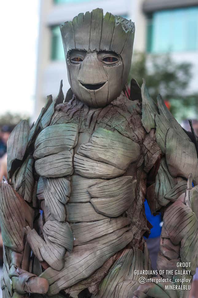 A cosplayer stands dressed as a smiling version of tree-based Marvel hero, Groot.