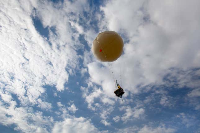 weather balloon floating into a cloudy sky