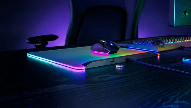A Razer Firefly V2 Pro on a desk with a mouse on top showing a rainbow of lights.