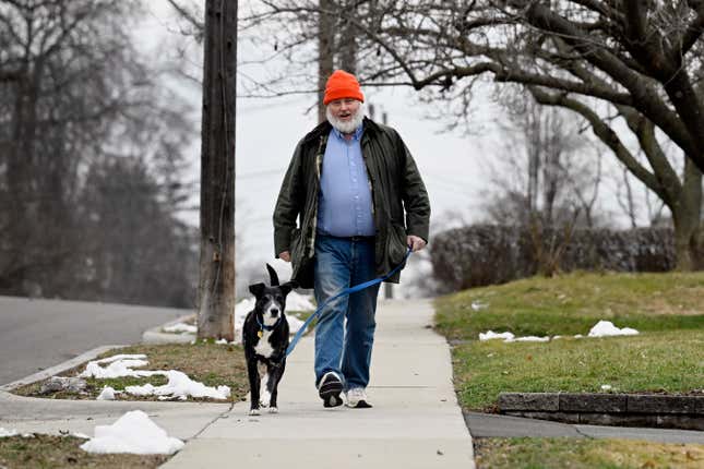 Casey Rosseau walks with his dog Darcy while listening to an e-book in West Hartford, Conn., Feb. 1, 2024. Rosseau, who estimates he reads about 200 books a year, said he&#39;d like to see more regulation of what publishers can charge libraries. Libraries have been grappling with soaring costs of digital titles, both e-books and audio books, that libraries typically lease from publishers for a year or two, with limited usage. (AP Photo/Jessica Hill)