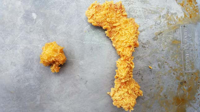 Popeyes chicken nugget next to Popeyes chicken strip on sheet tray