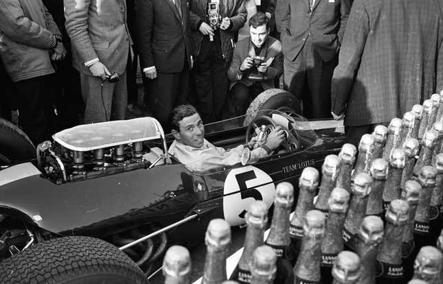 Der britische Motorsportmeister Jim Clark (1936 – 1968), Formel-1-Weltmeister von 1963 und 1965, fährt für das Lotus-Team auf der Rennstrecke von Brands Hatch, Kent.  Eine Reihe Champagnerflaschen wartet auf den Ausgang des Rennens.