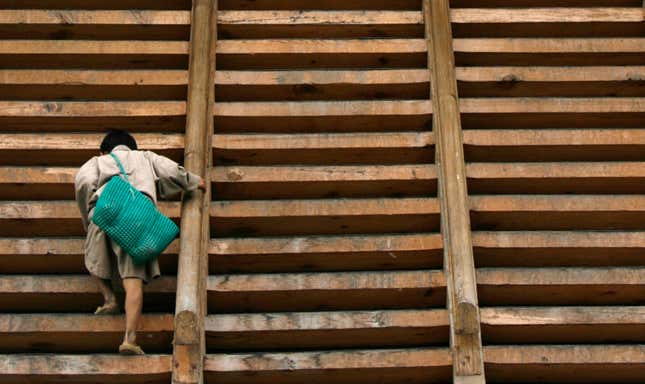A boy walks up a wooden staircase.
