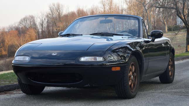 A 1993 black Mazda Miata stopped atop a hill