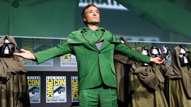 Robert Downey Jr. wears a green suit while standing in front of a crowd of Doctor Dooms during a panel at SDCC