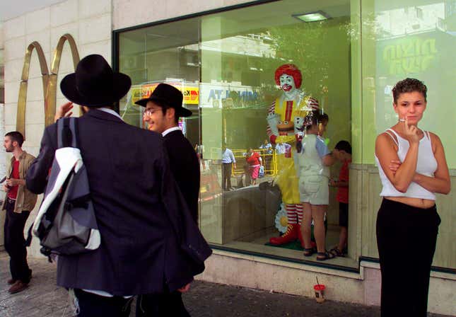 FILE - Residents of Jerusalem mingle inside and outside of the city&#39;s downtown McDonald&#39;s fast food restaurant Friday Aug. 16, 2002. McDonald’s is buying its restaurants in Israel from a longtime franchisee, hoping to reset sales that have slumped due to boycotts in the region. (AP Photo/David Guttenfelder, File)