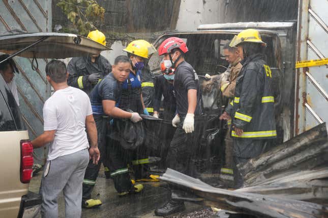 Firemen carry body bag of a victim of a fire in Quezon city, Philippines on Thursday, Aug. 31, 2023. A fire killed more than a dozen people Thursday in a small apparel factory in a Philippine residential area, where firefighters were delayed by flooding, traffic and a wrong address, a fire protection official. (AP Photo/Aaron Favila)