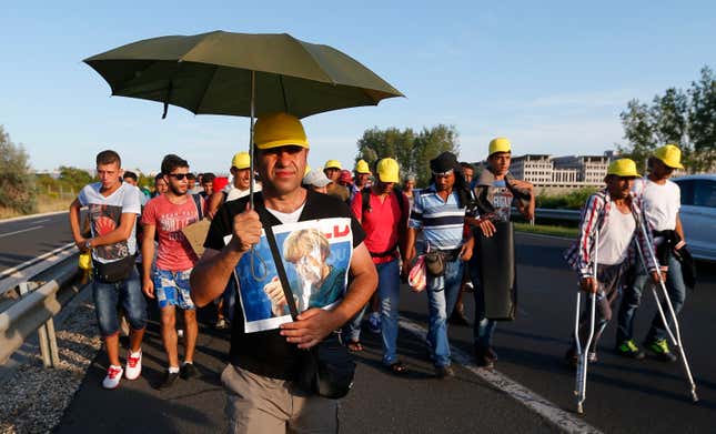 Image for article titled Photos: Fed up with the trains, migrants begin a long march down the highway in Hungary