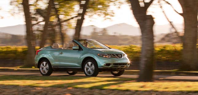 A turquoise Murano CrossCabriolet driving down a tree-lined street with the top down