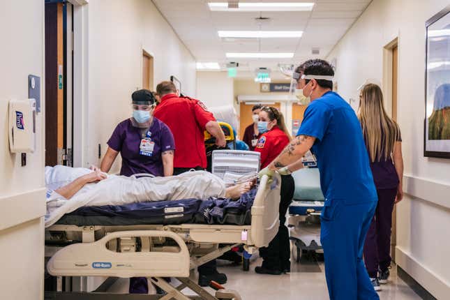Healthcare workers wearing masks and plastic face shields relocate a patient bed inside of Houston Methodist hospital.