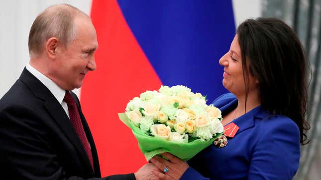 Russian President Vladimir Putin presents flowers to editor-in-chief of Russian state broadcaster RT, Margarita Simonyan, at the Kremlin in Moscow on May 23, 2019.