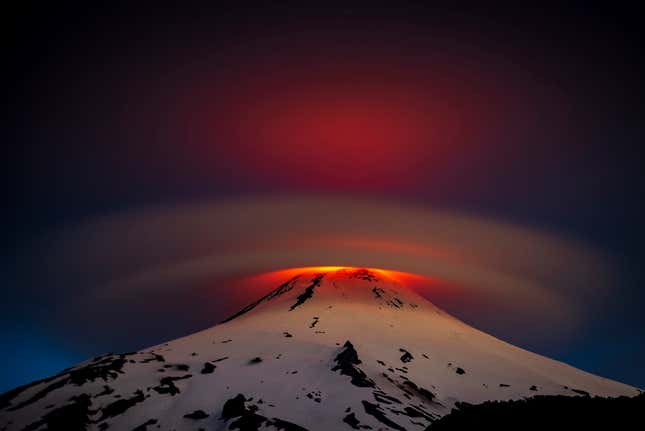 Una luz anaranjada premonitoria emana de una nube sobre el volcán Villarrica en Chile.