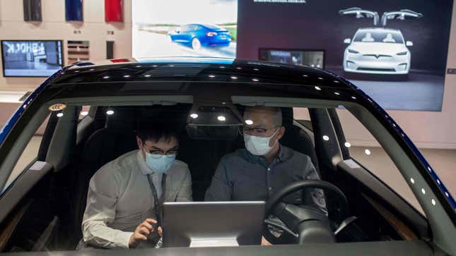 A man sits inside of a Tesla car Model 3 as a vendor talks to him at a Tesla shop inside of a shopping mall in Beijing on May 26, 2021. 