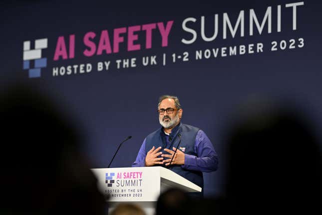 Rajeev Chandrasekhar speaking at a podium with the AI Safety Summit logo behind him