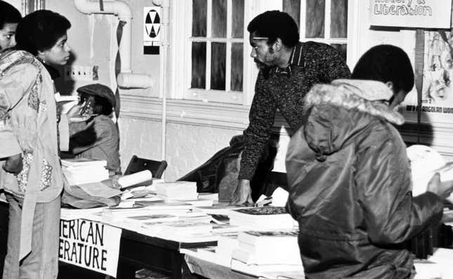 Une photographie de personnes autour de stands de librairies avec des livres sur l’histoire et la libération des Noirs, 1980. 