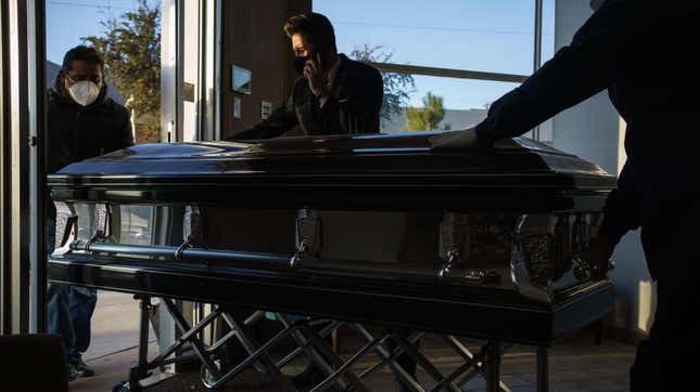 Jorge Ortiz (C), general manager of Perches Funeral Homes, watches as workers bring a casket in at Perches Funeral Home in El Paso, Texas, on December 4, 2020. -