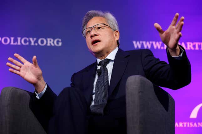 Jensen Huang sitting in a chair speaking with his hands up in front of a purple backdrop