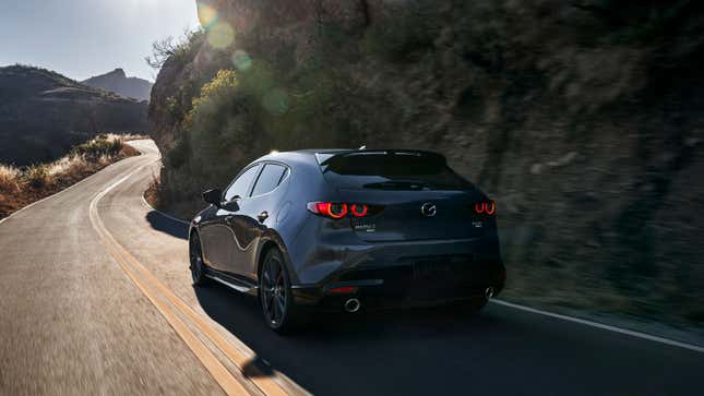 A photo fo a grey Mazda 3 Hatchback driving on a road. 