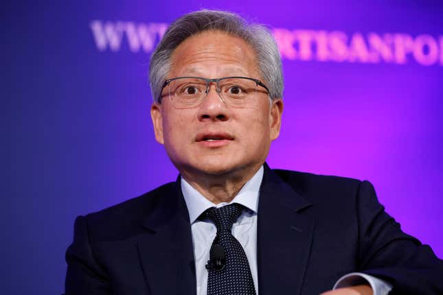 Jensen Huang with a surprised look on his face, wearing glasses, a black suit and tie with a blue button down in front of a purple backdrop