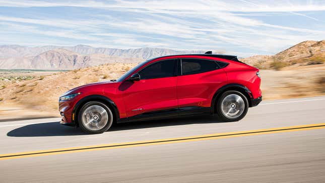 Profile view of a red Ford Mustang Mach-E on a desert road.