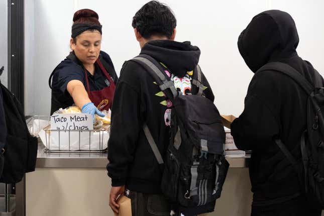 Cafeteria worker Melina Orozco serves lunch to students at Firebaugh High School in Lynwood, Calif. on Wednesday, April 3, 2024. Demand for school lunches has increased after California guaranteed free meals to all students regardless of their family&#39;s income. Now, districts are preparing to compete with the fast food industry for employees after a new law took effect guaranteeing a $20 minimum wage for fast food workers. (AP Photo/Richard Vogel)