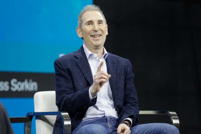 Andy Jassy sitting in a chair, pointing with his right hand