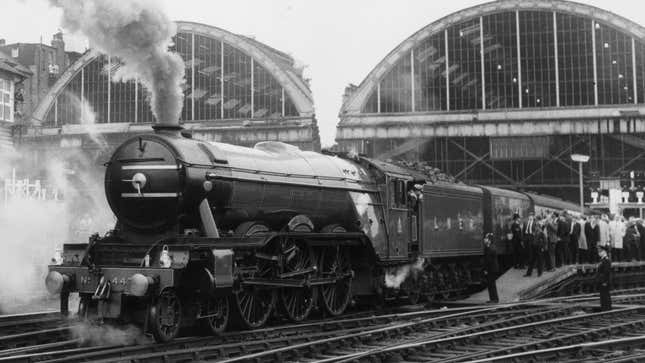 Ein Schwarzweißfoto des Dampfzugs Flying Scotsman in einem Bahnhof. 