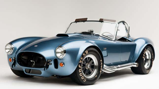 A photo of a pale blue Shelby Cobra in a studio. 