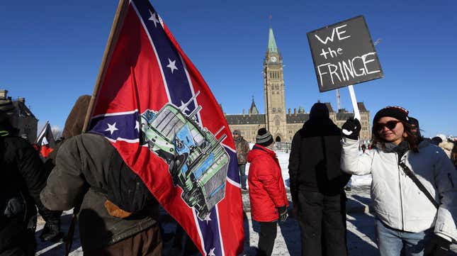 A supporter carries a US Confederate flag during the Freedom Convoy protesting Covid-19 vaccine mandates and restrictions in front of Parliament on January 29, 2022 in Ottawa, Canada. - Hundreds of truckers drove their giant rigs into the Canadian capital Ottawa on Saturday as part of a self-titled “Freedom Convoy” to protest vaccine mandates required to cross the US border. 