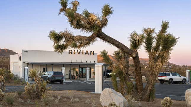 An exterior photo of the new Rivian Charging Outpost with a Joshua Tree in the foreground and two R1S charging