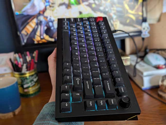 A keyboard is held up over a desk. 