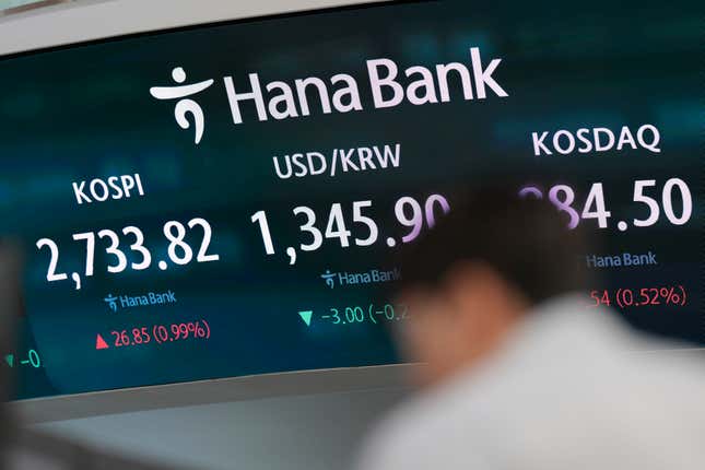 An employee of a bank stands near the screens showing the Korea Composite Stock Price Index (KOSPI), left, and the foreign exchange rate between the U.S. dollar and South Korean won at a foreign exchange dealing room in Seoul, South Korea, Thursday, April 4, 2024. Asian shares mostly rose Thursday after a firm finish on Wall Street, as expectations remained solid for U.S. interest rate cuts this year. (AP Photo/Lee Jin-man)