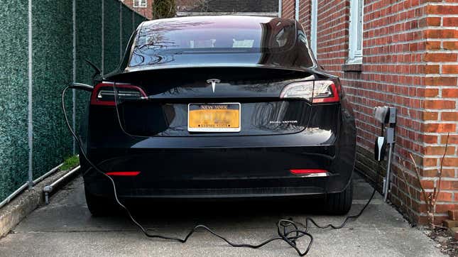 Tesla Electric Vehicle parked in driveway and plugged into charger, Queens, New York.