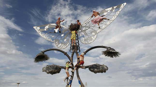 Burning Man participants climb on an art structure during the Burning Man festival.