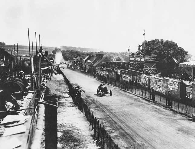 Zuschauer säumen die Strecke, während Jules Goux aus Frankreich am 12. Juli 1913 beim Grand Prix de l'Automobile Club de France auf der Rennstrecke von Amiens, Frankreich, den Peugeot EX3 Nr. 14 durch Moreuil fährt