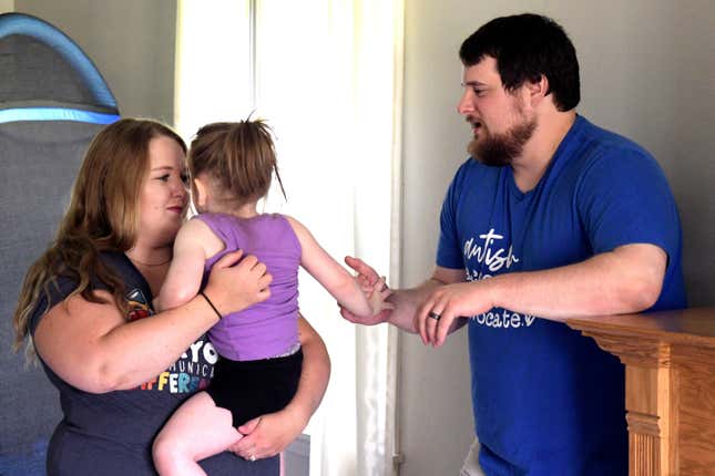 Lindsey and Kendrick Faulkner, hold their 2-year-old daughter, Aria, at their home in Peoria, Ill. during an early intervention therapy session on Aug. 15, 2023. (AP Photo/Ron Johnson)