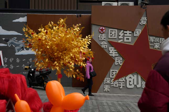 A women walks past a display depicting a golden tree and government propaganda calling for patriotism and unity between society and military at a mall in Beijing, Wednesday, Jan. 17, 2024. China&#39;s economy for the October-December quarter grew at a quicker rate, allowing the Chinese government to hit its target of about 5% annual growth for 2023 even though trade data and the economic recovery remain uneven. (AP Photo/Ng Han Guan)