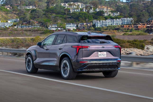 A press photo of a gunmetal grey Blazer EV driving near the ocean