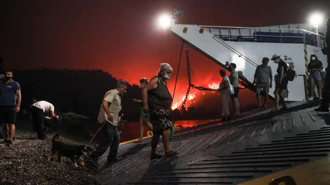 People board a ferry prior to an evacuation as a wildfire approaches the seaside village of Limni on the island of Evia, Greece, on August 6, 2021.