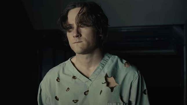 Lewis Pullman as Bob stands wearing a bullet-riddled shirt