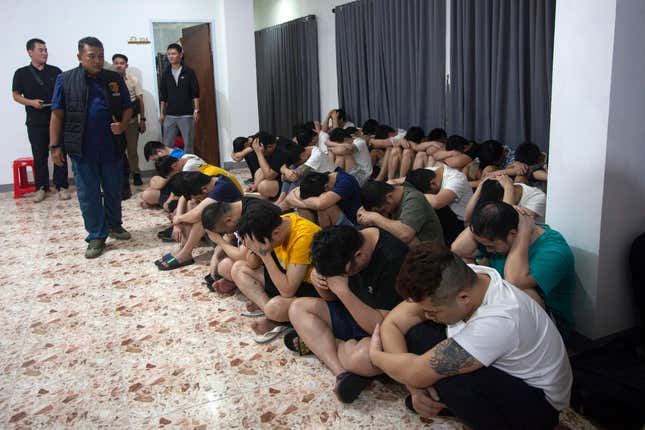 Plain-clothed police officers detain Chinese nationals following a raid on a shophouse in Batam, Indonesia, Tuesday, Aug. 29, 2023. Indonesian police said Wednesday they have arrested a number of Chinese citizens for involvement in a cross-border telephone and online romance scam syndicate after receiving a tip from the Chinese security ministry. (AP Photo/Andaru)