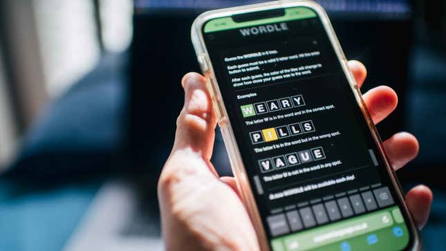 A hand holding a cellphone playing Wordle.